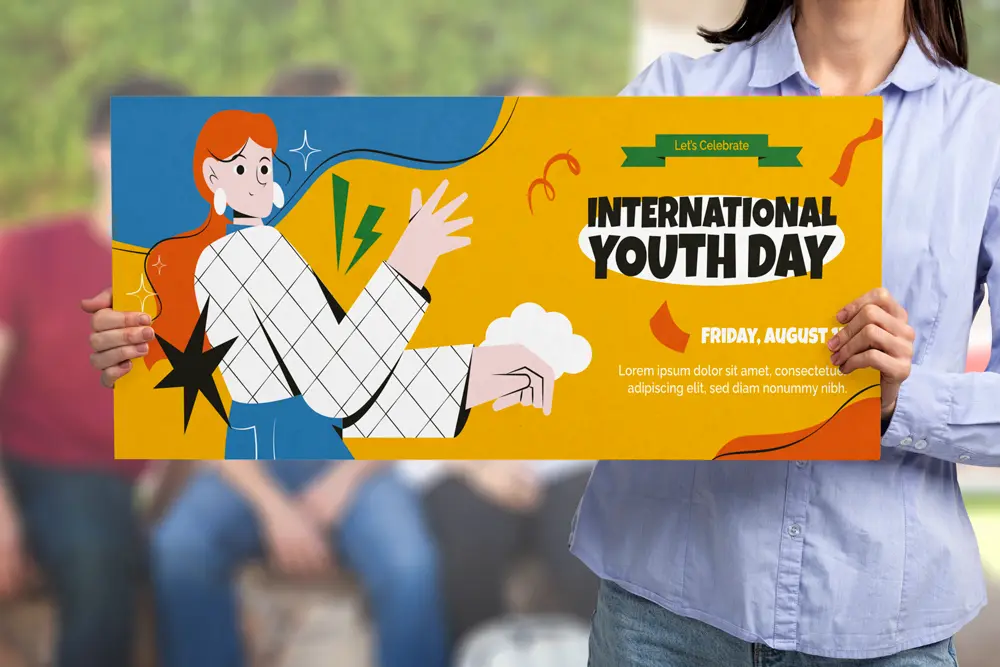 A person holding a colorful foam boards prints sign promoting "International Youth Day." The design features a bold illustration of a red-haired character in a white checkered shirt with vibrant yellow, blue, and orange background elements. The text highlights the event date as "Friday, August" with placeholder text below.